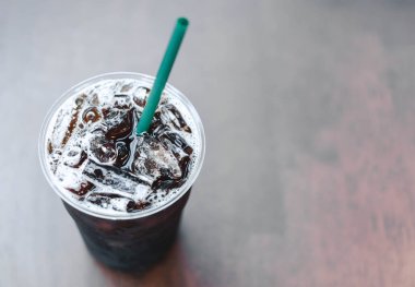 Bir bardak buzlu americano kahvesini ahşap masaya koy, seçici odaklı.