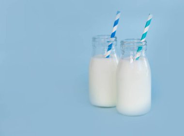 Açık mavi arka planda saman ile bir şişe taze süt, sağlıklı yiyecek kavramı