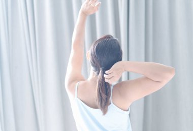 Kapalı kadın yatakta oturuyor ve sabah uyanıp dinlenmek için esniyor.