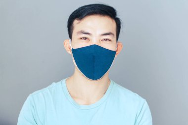 Hava akımını korumak için yüz maskesi takan yakın plan Asyalı bir adam ya da gri geçmişi, sağlık hizmetleri ve tıbbi konsepti olan virüslü covid 19.