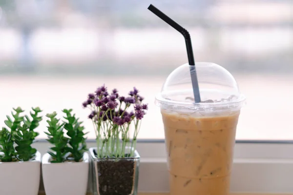 Closeup glass of ice coffee with flower pot in the coffee shop