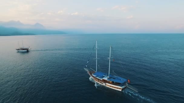 Luftaufnahme eines schwimmenden Schiffes in einer Bucht mit tiefblauem Wasser. Sonnenuntergang auf See, aufgenommen in 4k uhd — Stockvideo
