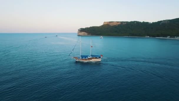 Vista aérea del barco de natación en una bahía con Depp Blue Water. Puesta de sol en el mar, disparo en 4K UHD — Vídeo de stock