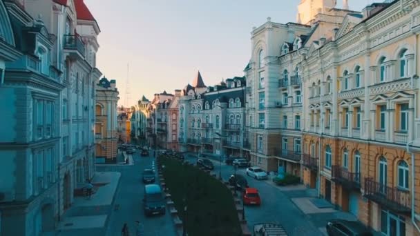 Câmera Drone se move no nível dos telhados dos edifícios nas ruas europeias estreitas velhas com casas coloridas e pedestres ao pôr do sol, filmado em 4K UHD — Vídeo de Stock