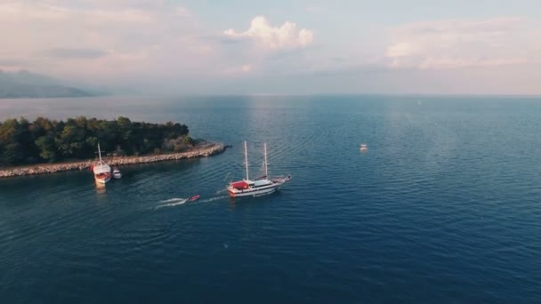 Luftaufnahme eines großen Schiffes, das ein Boot in der Bucht mit tiefblauem Wasser bei Sonnenuntergang schleppt, aufgenommen in 4k uhd — Stockvideo