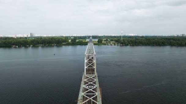 Luftaufnahme des Personenzuges auf der Eisenbahnbrücke über den Fluss in der Megapolis bei Sonnenuntergang, aufgenommen in 4k uhd — Stockvideo