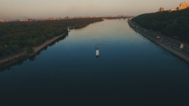 Лодка плывет вдоль реки возле европейского речного города на закате — стоковое видео