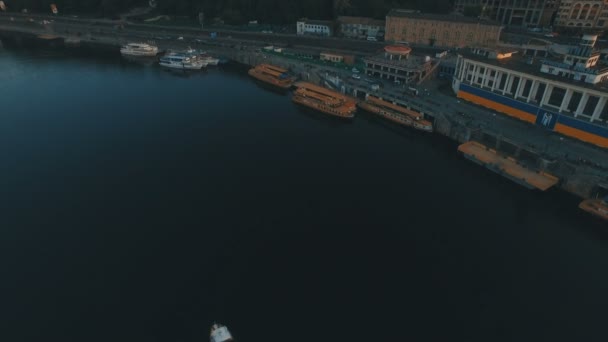 Das Boot fährt bei Sonnenuntergang entlang des Flusses in der Nähe der europäischen Flussstadt — Stockvideo