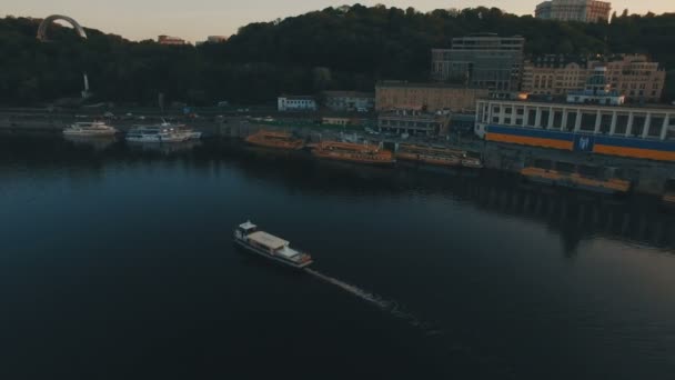 El barco navega a lo largo del río cerca de la ciudad del río europeo al atardecer — Vídeos de Stock