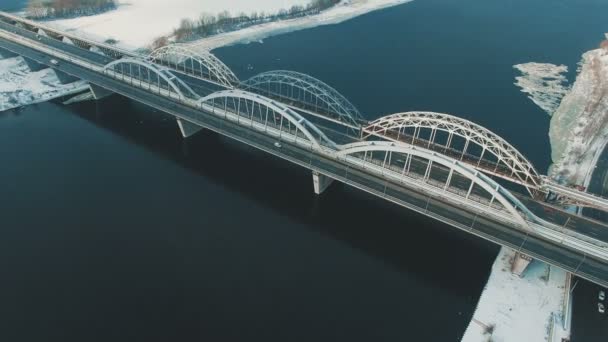 Auto's en trein beweegt op een brug over een bevroren rivier luchtfoto drone beeldmateriaal — Stockvideo