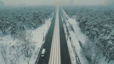 Arabalar ve tramvay ile kış orman yolda üstten görünüm yukarıda. Kar yağışı hava dron görüntüleri