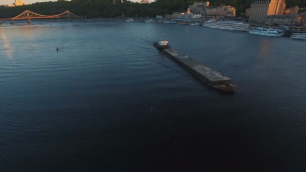 Баржа вітрила вздовж річки поблизу міського порту на заході сонця повітряні кадри — стокове відео
