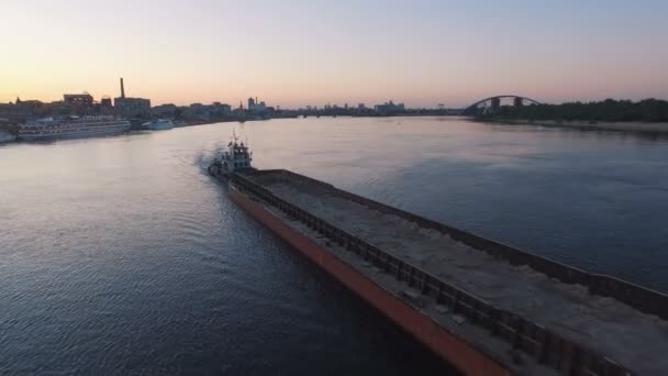 Barcaza navega a lo largo del río cerca del puerto de la ciudad en el atardecer imágenes aéreas — Vídeo de stock