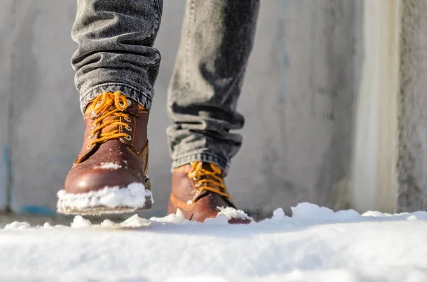 El hombre camina por la calle de la nieve. Pies calzados en botas de invierno marrones. Invierno camina concepto — Foto de Stock