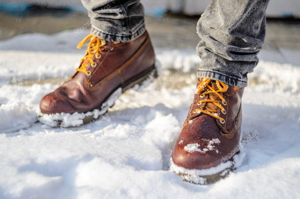 Man walks in the snow. Feet shod in brown winter boots. Winter boots concept