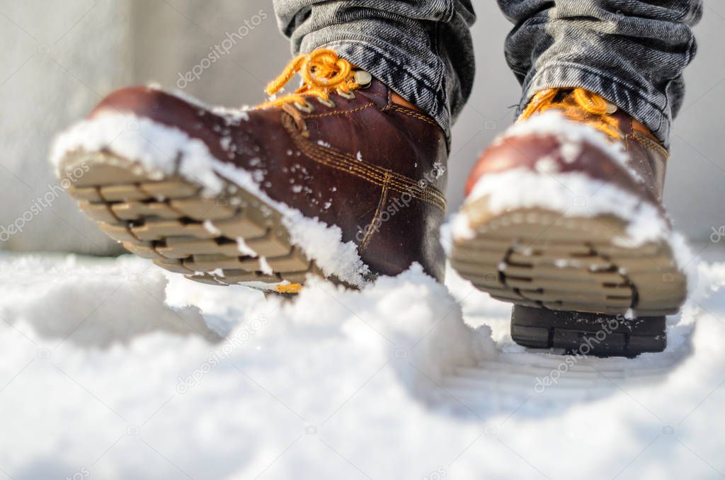 Brown leather shoes in the snow. Legs in the warmth concept