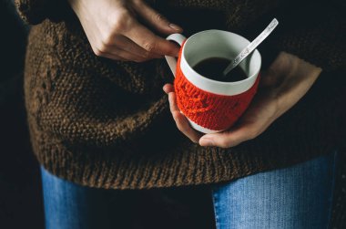 Kırmızı örgü yün Kupası kadın elinde kalp desenli.