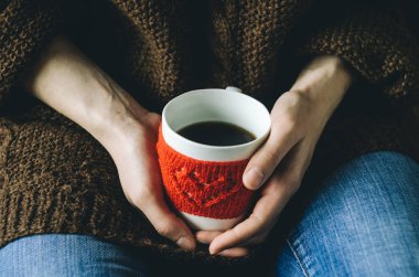 Kırmızı örgü yün Kupası kadın elinde kalp desenli.