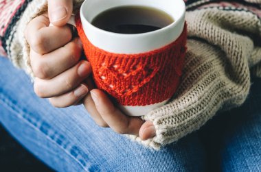 Kırmızı örgü yün Kupası kadın elinde kalp desenli.