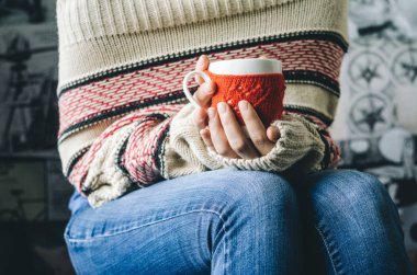 Kırmızı örgü yün Kupası kadın elinde kalp desenli.