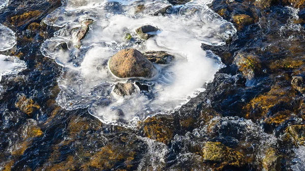 Floden forsar med stenar och isiga fläckar — Stockfoto