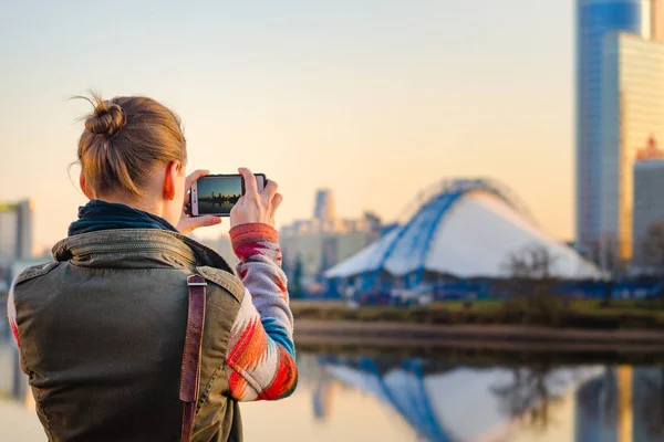 Ung kvinna tar bilder av staden på en smartphone — Stockfoto