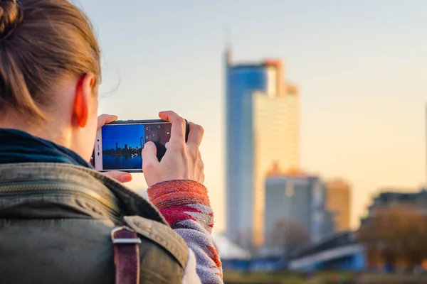 Ung kvinna tar bilder av staden på en smartphone — Stockfoto