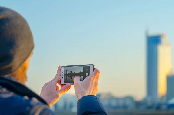 Ung man tar bilder av staden på en smartphone — Stockfoto