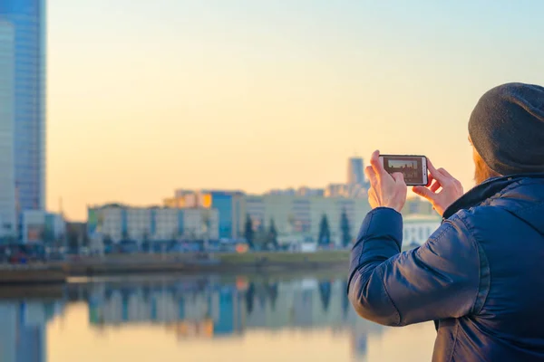 Ung man tar bilder av staden på en smartphone — Stockfoto