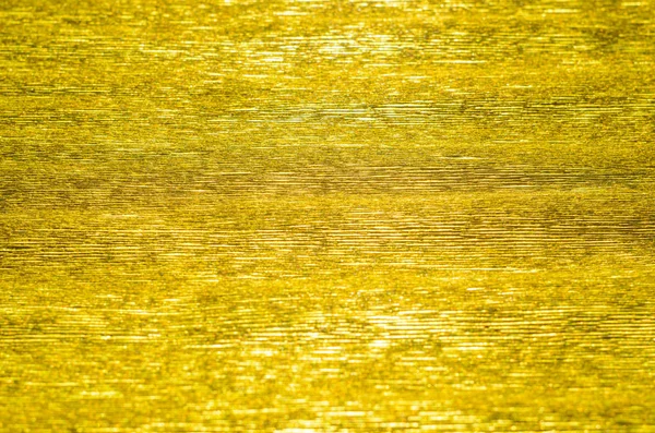 Gold Texture of Embossed Paper. Gold Paper Texture Background. Abstract background with deep grooves in the texture of corrugated paper. Pattern of horizontal grooves