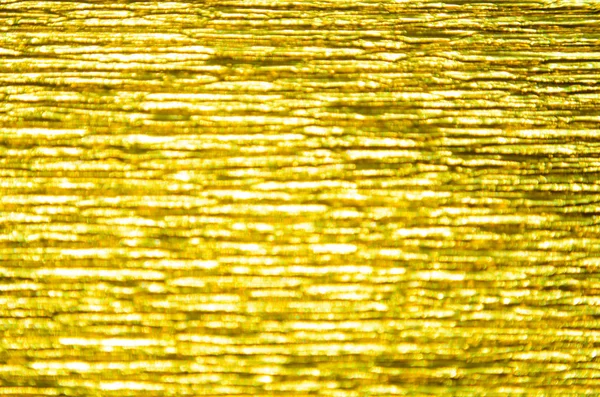 Gold Texture of Embossed Paper. Gold Paper Texture Background. Abstract background with deep grooves in the texture of corrugated paper. Pattern of horizontal grooves
