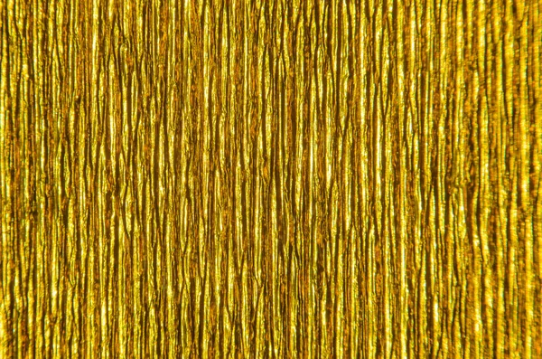 Gold Texture of Embossed Paper. Gold Paper Texture Background. Abstract background with deep grooves in the texture of corrugated paper. Pattern of vertical grooves