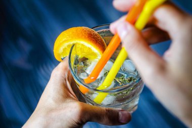 Buz bir portakal dilimi ve biberiye ile dekore edilmiş, cin tonik