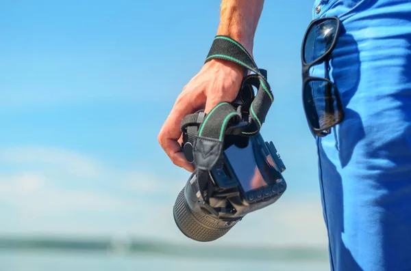 DSLR fényképezőgép, egy férfi keze közelről ellen egy tengeri horizont — Stock Fotó