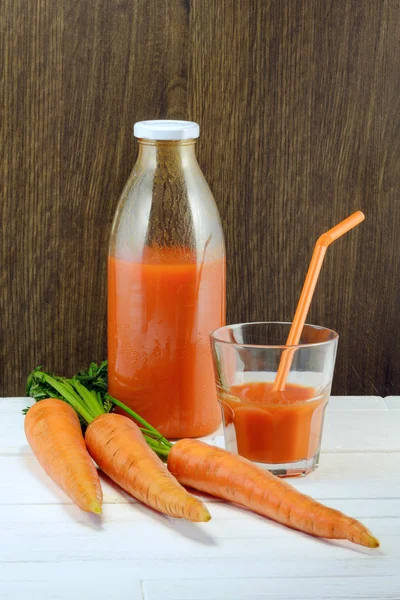 A bottle of carrot juice and a glass of carrot juice still life