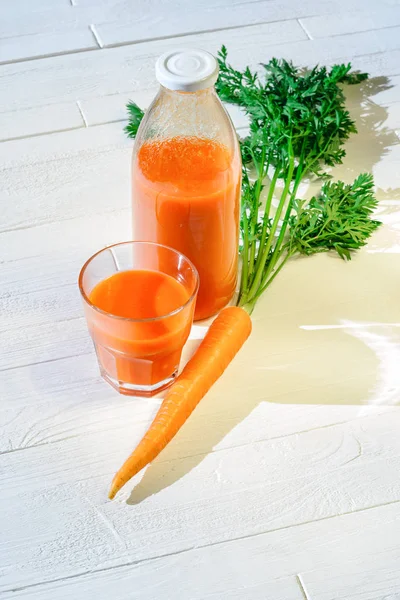 Láhev mrkvové šťávy s plněný sklem — Stock fotografie