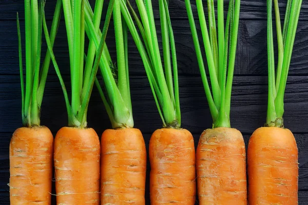 Carrots on black wood background top view