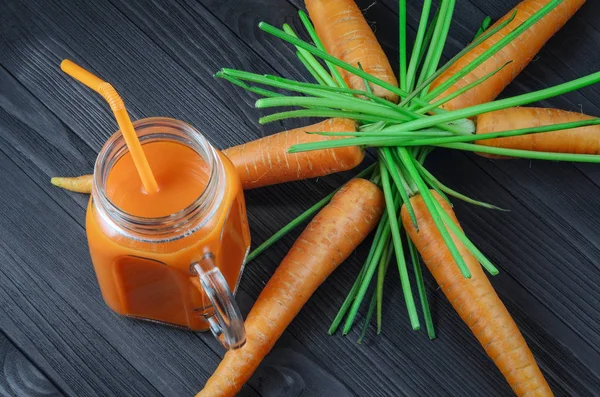 Carrot juice in a glass jar with fresh carrots