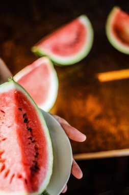 Dilim karpuz ellerinde beyaz plaka üzerinde