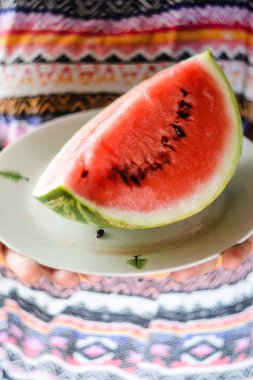 Dilim karpuz ellerinde beyaz plaka üzerinde