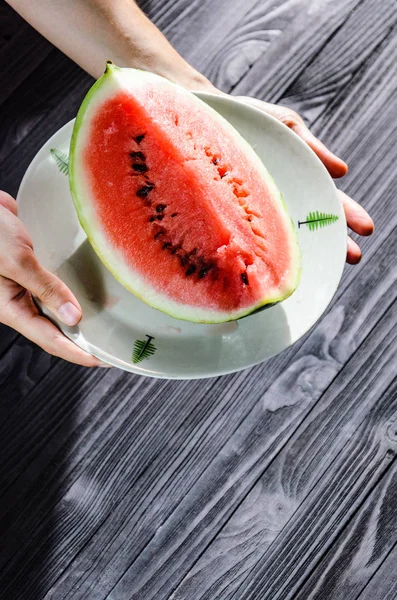 Fatia de melancia na placa branca a mãos — Fotografia de Stock