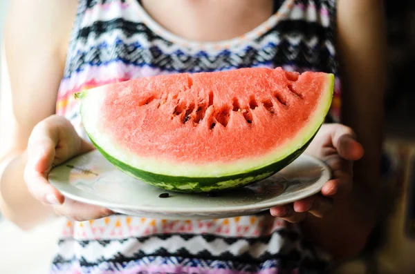Fatia de melancia na placa branca a mãos — Fotografia de Stock
