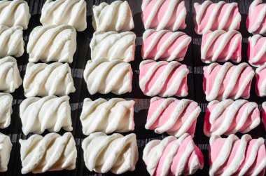 Beyaz ve pembe şekerleme düzgünce siyah ahşap bir masa üzerinde ortaya koydu. Taze ve tatlı şekerleme arka plan