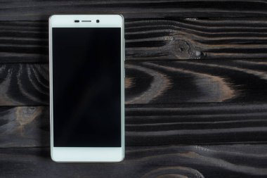 Koyu ahşap masa üstünde beyaz smartphone.