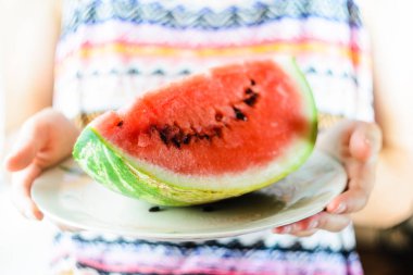 Dilim karpuz ellerinde beyaz plaka üzerinde