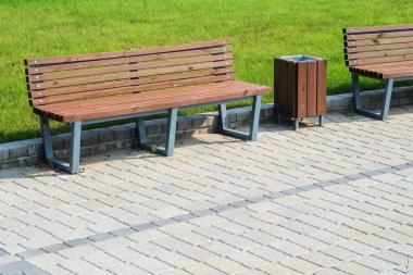 Yeşil çim karşı döşeli yol üzerindeki bir yaz parkta iki şık banklar ve bir çöp olabilir. Küçük mimarlık şekiller kavramı