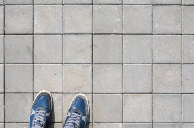 Beton blok kaldırım üzerinde mavi spor ayakkabı