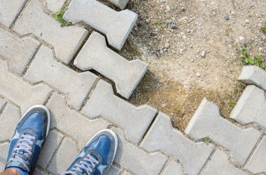 Beton blok kaldırım üzerinde mavi spor ayakkabı