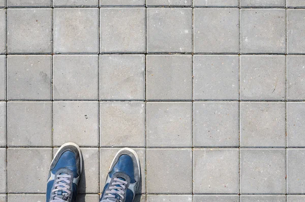 Beton blok kaldırım üzerinde mavi spor ayakkabı