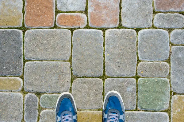 Beton blok kaldırım üzerinde mavi spor ayakkabı